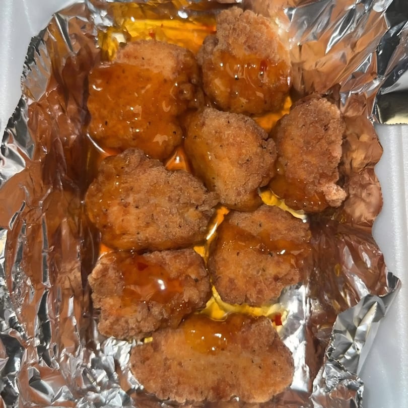Jimmy's Hot Chicken & Market's fried chicken nuggets drizzled with a sweet orange sauce in foil.