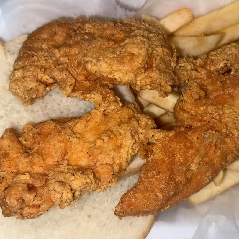 Crispy fried chicken tenders and french fries served on white bread from Jimmy's Hot Chicken.