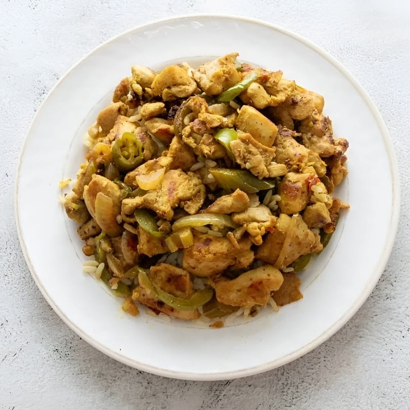 A white plate filled with Jimmy's Hot Chicken, green peppers, onions, and rice.